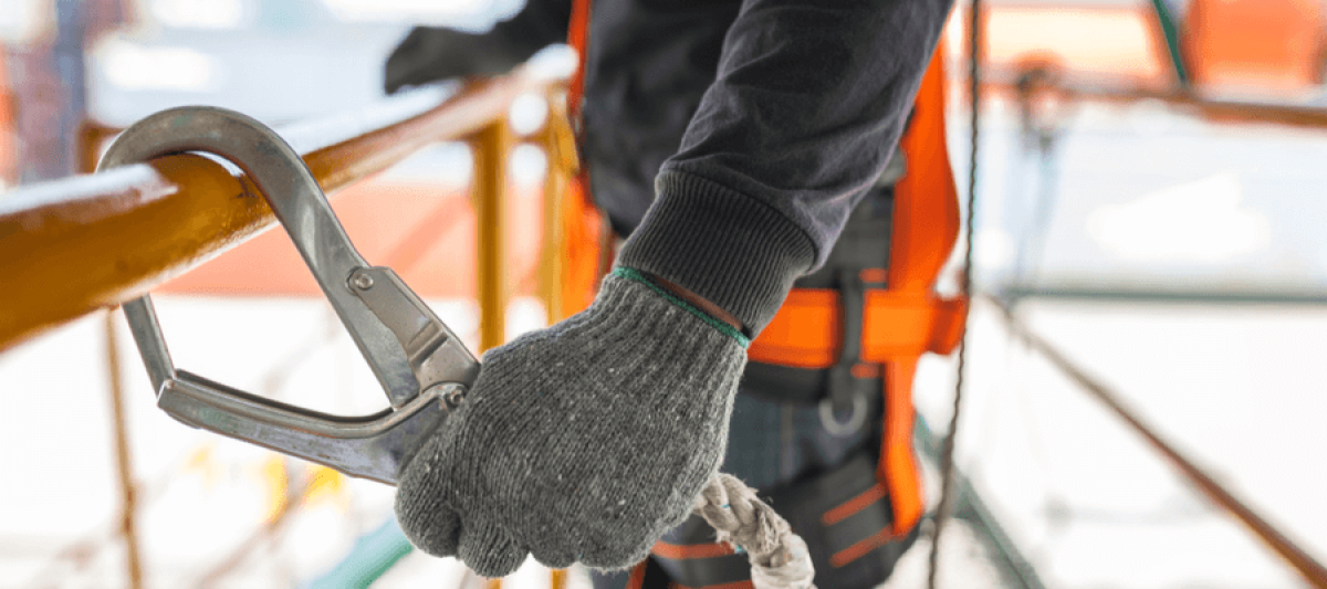 Construction worker wearing safety harness and safety line working on construction site, OSHA fall prevention and protection